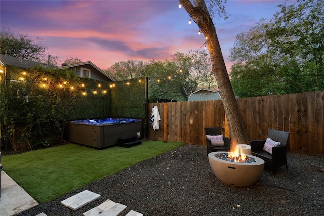 yard at dusk featuring a hot tub and an outdoor fire pit