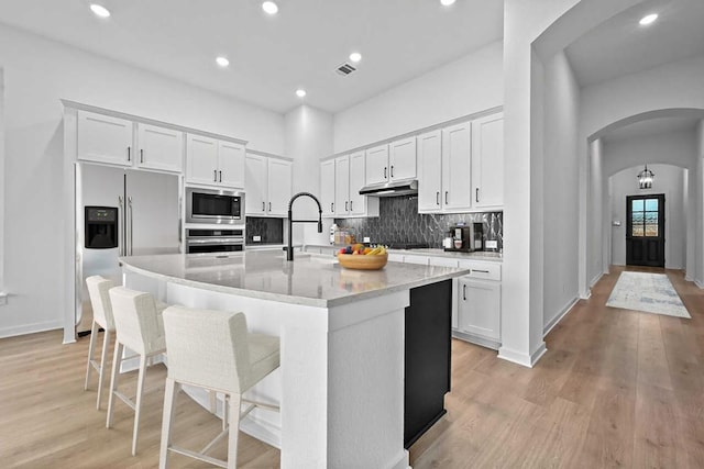 586 Biscayne Bay Bnd, Kyle, TX 78640 - kitchen with appliances with stainless steel finishes, arched walkways, white cabinets, backsplash, and recessed lighting