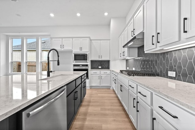 586 Biscayne Bay Bnd, Kyle, TX 78640 - kitchen with appliances with stainless steel finishes, white cabinetry, light stone countertops, light wood-style flooring, and recessed lighting