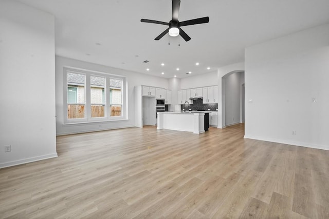 586 Biscayne Bay Bnd, Kyle, TX 78640 - unfurnished living room featuring ceiling fan, arched walkways, light wood-style floors, and recessed lighting
