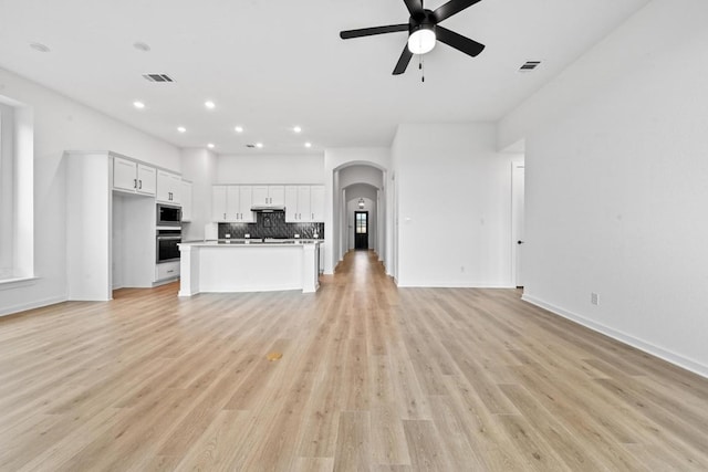 586 Biscayne Bay Bnd, Kyle, TX 78640 - unfurnished living room featuring a ceiling fan, arched walkways, light wood finished floors, and recessed lighting