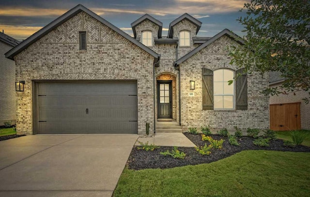 586 Biscayne Bay Bnd, Kyle, TX 78640 - french country style house featuring concrete driveway, an attached garage, brick siding, and a lawn