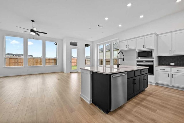 586 Biscayne Bay Bnd, Kyle, TX 78640 - kitchen featuring stainless steel appliances, open floor plan, white cabinets, light wood-style floors, and recessed lighting