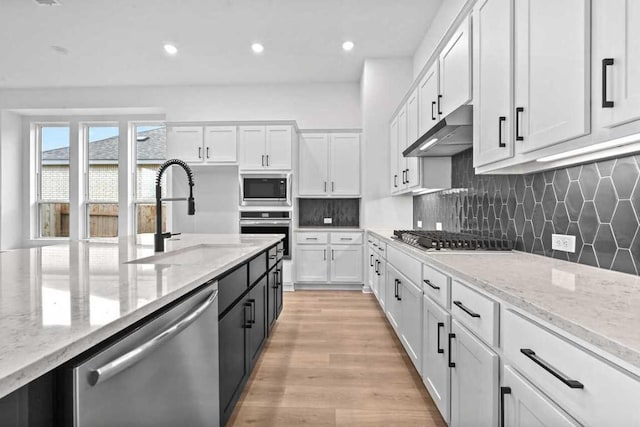 586 Biscayne Bay Bnd, Kyle, TX 78640 - kitchen with stainless steel appliances, white cabinetry, light stone counters, light wood-style floors, and recessed lighting