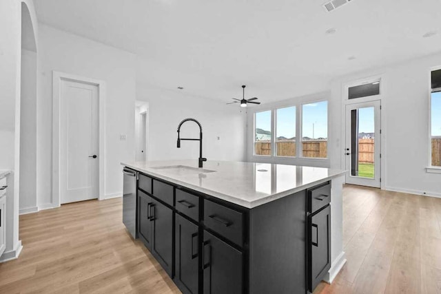 586 Biscayne Bay Bnd, Kyle, TX 78640 - kitchen featuring dark cabinets, a ceiling fan, light wood-style flooring, and light countertops