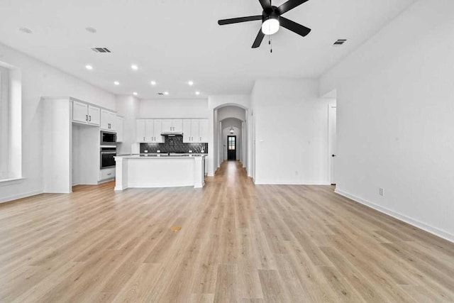 586 Biscayne Bay Bnd, Kyle, TX 78640 - unfurnished living room featuring a ceiling fan, arched walkways, light wood-type flooring, and recessed lighting