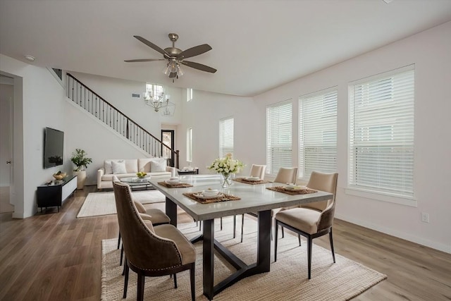 dining space with baseboards, stairway, a high ceiling, and wood finished floors