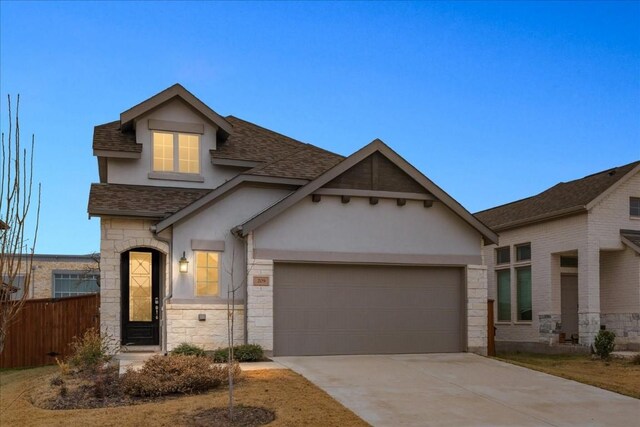 view of front of home with roof with shingles, stucco siding, driveway, stone siding, and an attached garage