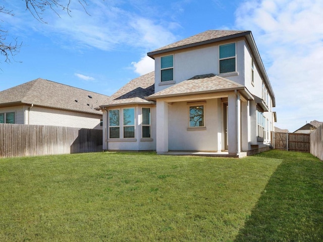 back of house featuring a shingled roof, a yard, a fenced backyard, and stucco siding