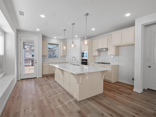 kitchen with light wood-type flooring, visible vents, a sink, stainless steel appliances, and light countertops