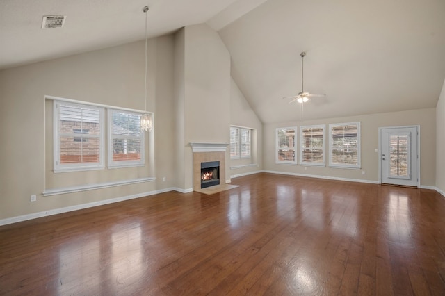 unfurnished living room featuring ceiling fan, dark hardwood / wood-style flooring, a tiled fireplace, and high vaulted ceiling