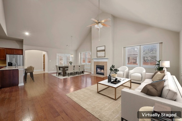 living room featuring hardwood / wood-style flooring, a fireplace, high vaulted ceiling, and ceiling fan