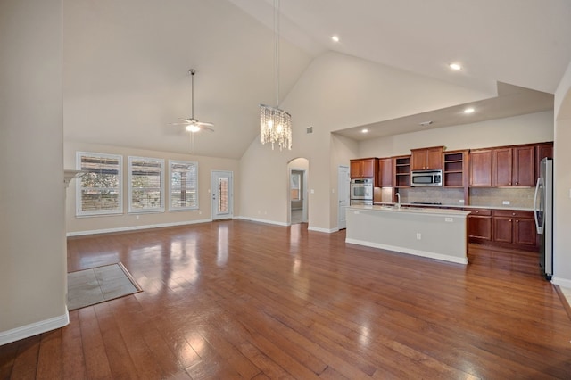 kitchen with appliances with stainless steel finishes, backsplash, dark hardwood / wood-style flooring, a kitchen island with sink, and ceiling fan