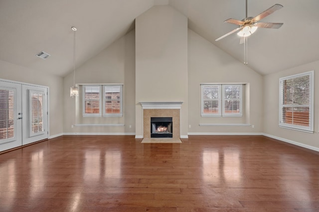 unfurnished living room featuring a tiled fireplace, dark wood-type flooring, high vaulted ceiling, and ceiling fan