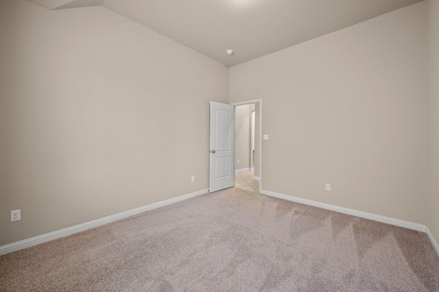 carpeted spare room with lofted ceiling