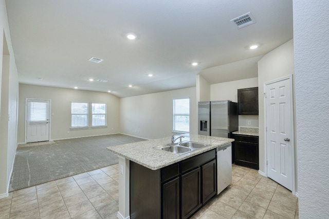 kitchen featuring vaulted ceiling, appliances with stainless steel finishes, sink, light colored carpet, and a center island with sink