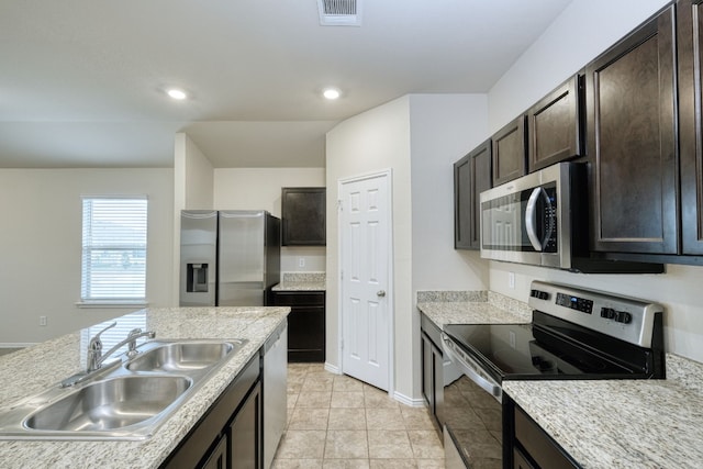 kitchen featuring sink, light stone counters, dark brown cabinets, light tile patterned floors, and appliances with stainless steel finishes