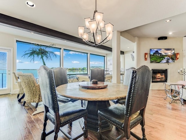 dining area with a water view, a chandelier, and light wood-type flooring