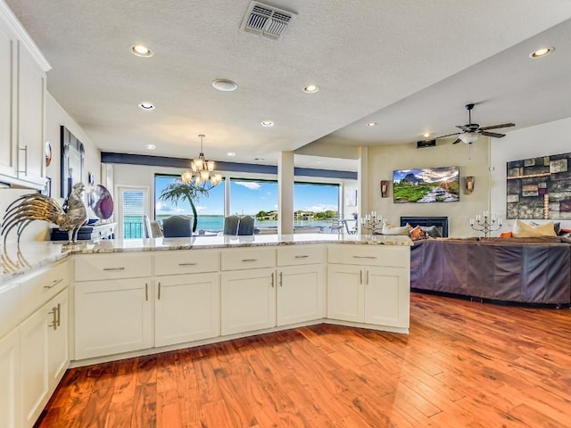 kitchen featuring light stone countertops, kitchen peninsula, and white cabinets