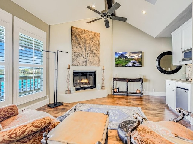 living room featuring vaulted ceiling, ceiling fan, and light hardwood / wood-style flooring