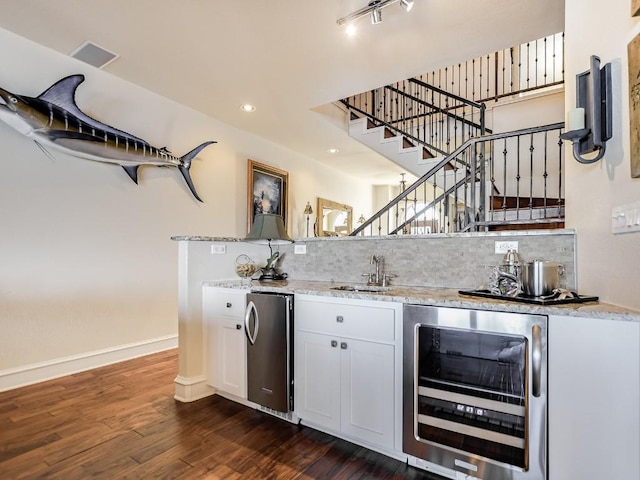 bar featuring white cabinetry, stainless steel fridge, dark hardwood / wood-style floors, beverage cooler, and backsplash