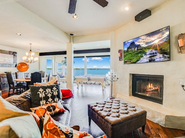 living room with a premium fireplace, wood-type flooring, and ceiling fan with notable chandelier