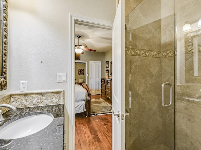 bathroom featuring ceiling fan, vanity, a shower with door, and hardwood / wood-style floors