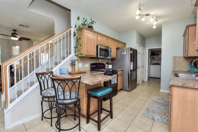 kitchen featuring light tile patterned floors, sink, a breakfast bar, appliances with stainless steel finishes, and backsplash