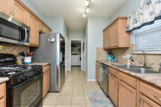 kitchen with sink, washer and clothes dryer, backsplash, stainless steel appliances, and light tile patterned flooring