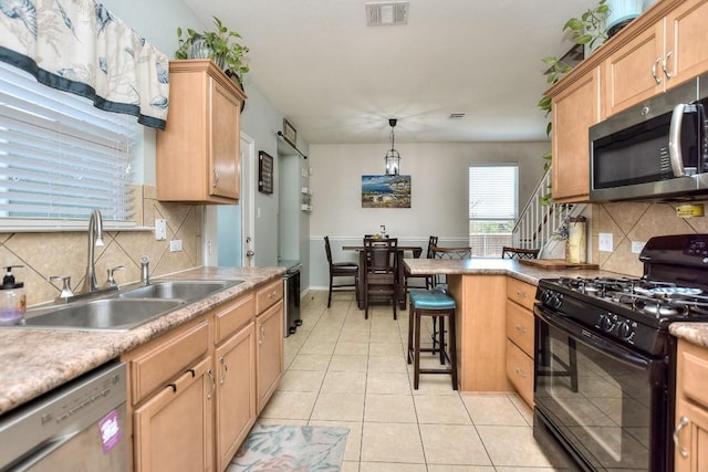 kitchen with a breakfast bar, decorative light fixtures, sink, light tile patterned floors, and stainless steel appliances