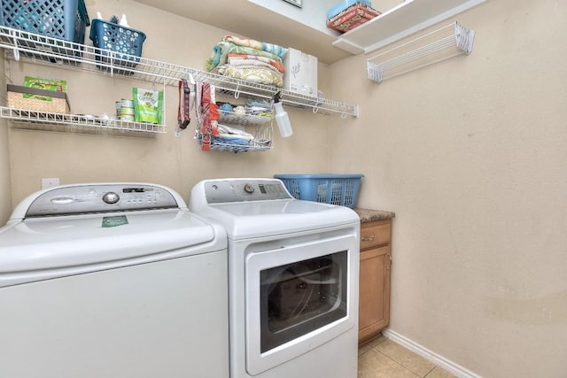 washroom featuring cabinets, washing machine and dryer, and light tile patterned floors