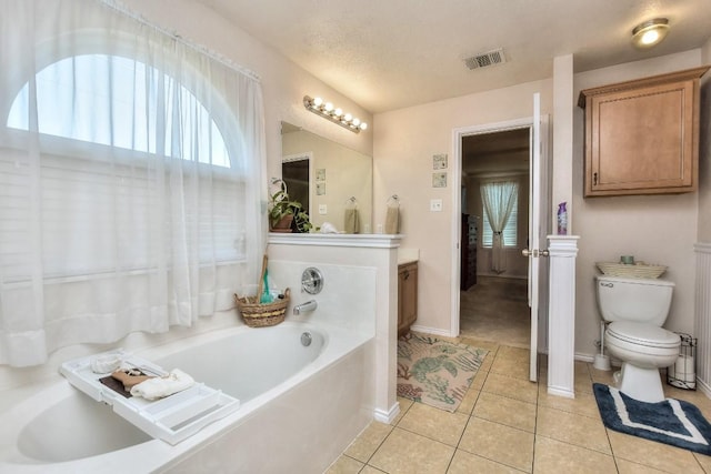 bathroom featuring tile patterned flooring, vanity, a washtub, toilet, and a textured ceiling