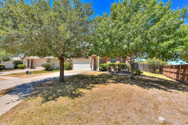 view of property hidden behind natural elements with a garage and a front lawn