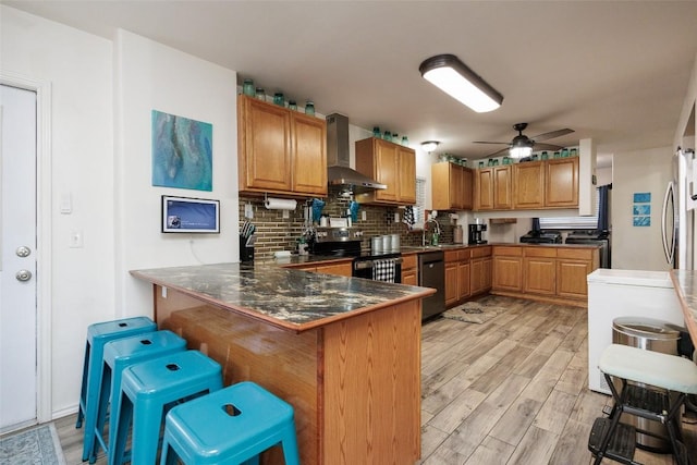 kitchen with dishwasher, a breakfast bar area, wall chimney exhaust hood, kitchen peninsula, and electric stove