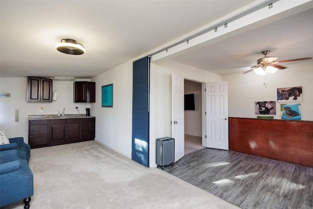 living room featuring ceiling fan, a barn door, indoor wet bar, and light wood-type flooring