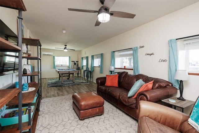 living room featuring light hardwood / wood-style flooring, an AC wall unit, ceiling fan, and vaulted ceiling