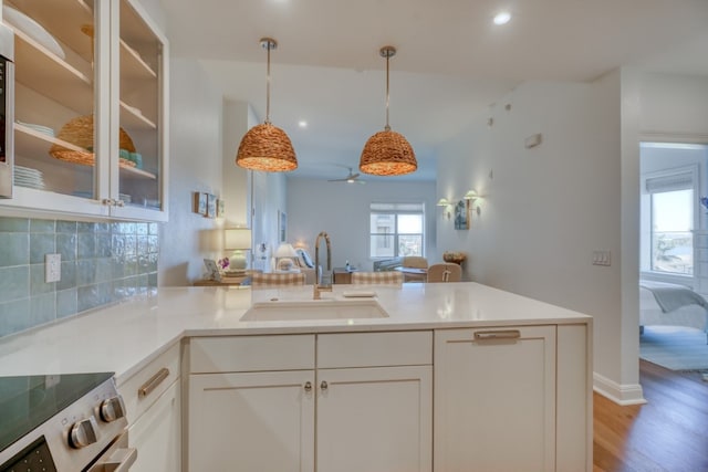 kitchen with sink, stainless steel electric range, decorative backsplash, white cabinets, and decorative light fixtures