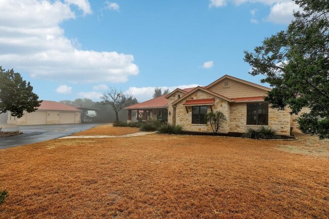 ranch-style house featuring stone siding and a front yard