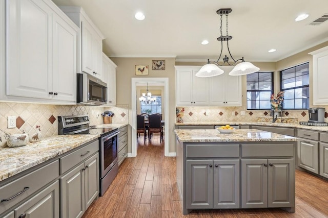 kitchen with gray cabinetry, white cabinetry, appliances with stainless steel finishes, a kitchen island, and pendant lighting