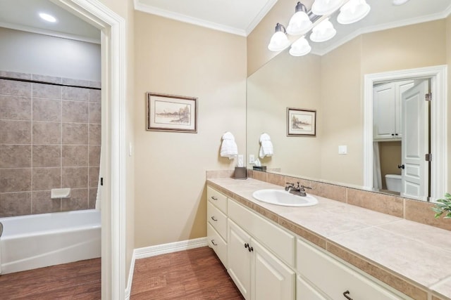 bathroom featuring crown molding, vanity, wood finished floors, toilet, and baseboards