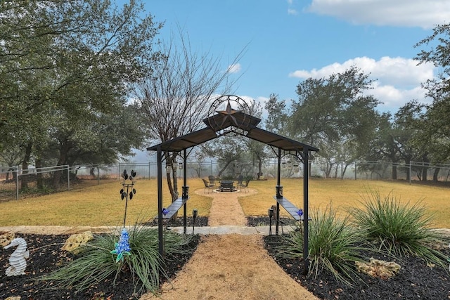 view of property's community featuring a yard, fence, and a fire pit