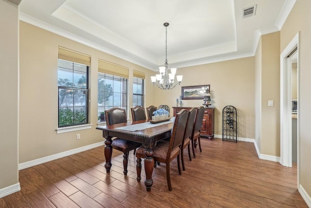 dining area with a raised ceiling, a chandelier, wood finished floors, crown molding, and baseboards