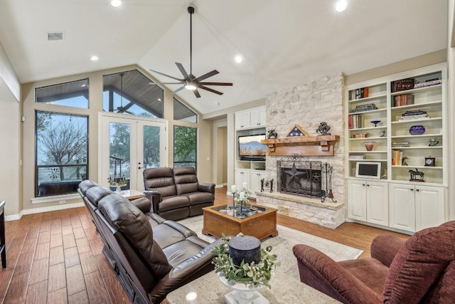 living room featuring french doors, ceiling fan, a fireplace, and light hardwood / wood-style flooring