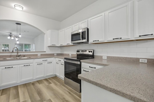 kitchen featuring stainless steel appliances, sink, pendant lighting, and white cabinets