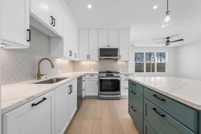 512 W Saint Johns Ave Unit A, Austin, TX 78752 - kitchen with appliances with stainless steel finishes, a sink, white cabinetry, light wood-style floors, and backsplash