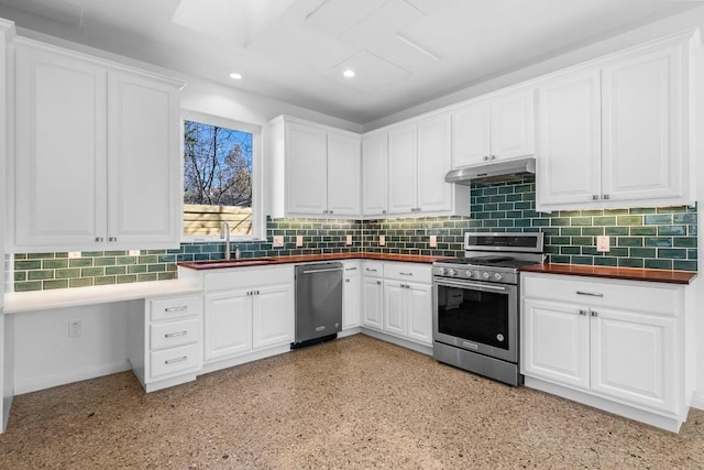 kitchen with dark countertops, under cabinet range hood, decorative backsplash, appliances with stainless steel finishes, and a sink