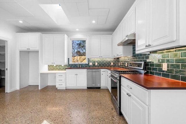 kitchen with under cabinet range hood, white cabinets, dark countertops, and appliances with stainless steel finishes