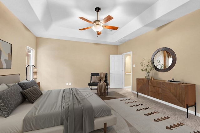 bedroom with ceiling fan, a tray ceiling, and carpet floors