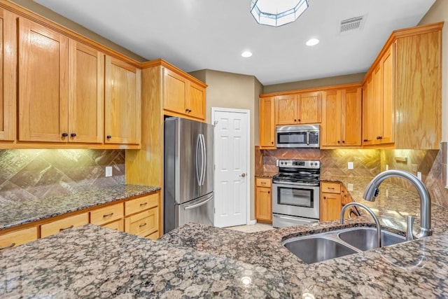 kitchen featuring dark stone countertops, sink, backsplash, and stainless steel appliances