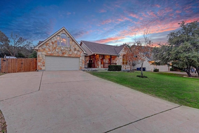 view of front of house with stone siding, a lawn, driveway, and fence